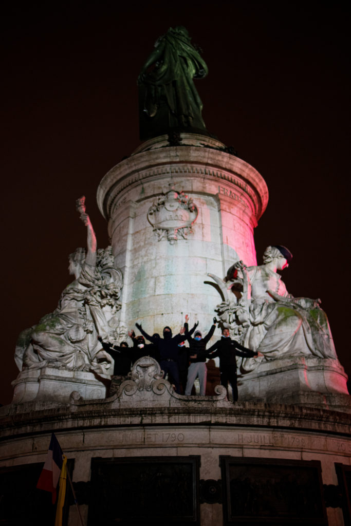 Des militants antifascistes ayant gravis la fontaine de la place de la République à Paris lancent un "clapping"  durant la manifestation contre la proposition de loi dite Sécurité Globale le 5 décembre 2020.