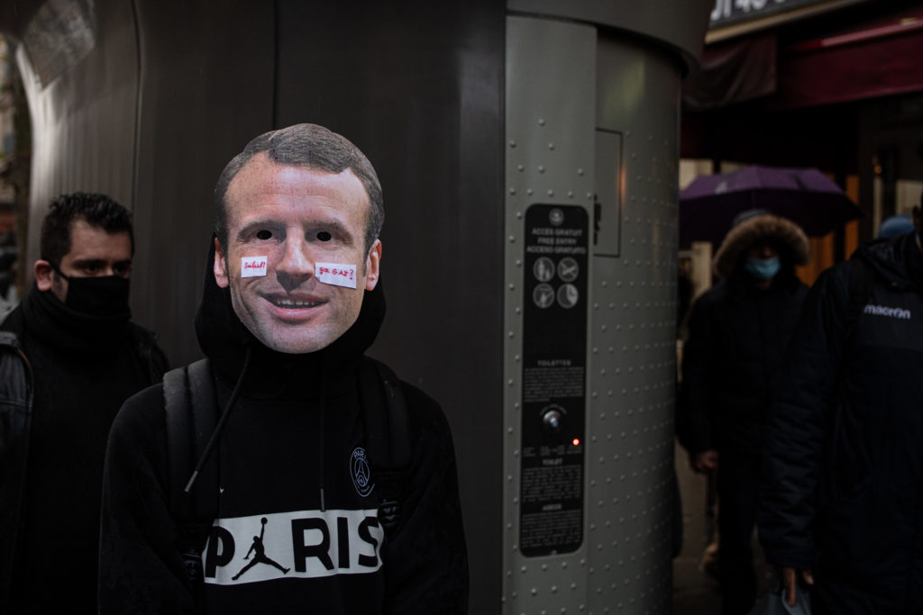 Un manifestant porte un masque représentant le visage d'Emmanuel Macron avec le message "salut ça gaz?", lors de la manifestation contre la proposition de loi dite Sécurité Globale le 12 décembre 2020.