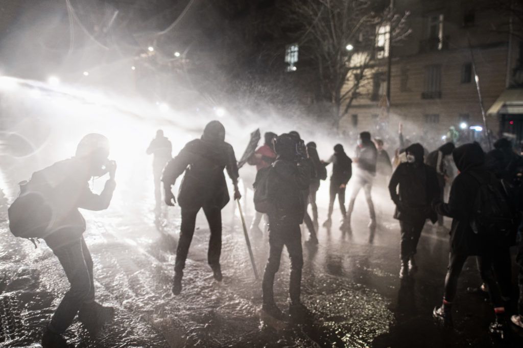 Le 21 novembre 2020, une personnne semble en lévitation dos à la police qui asperge les manifestants avec un canon à eau à la fin de la manifestation contre la proposition de loi Sécurité globale