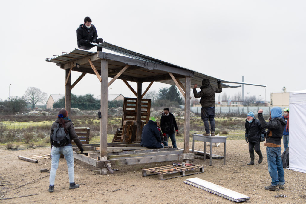 Des militants montent la dernière tôle achevant ainsi le toit de la première cabane en bois de la ZAD, le 8 février 2021 à Gonesse.