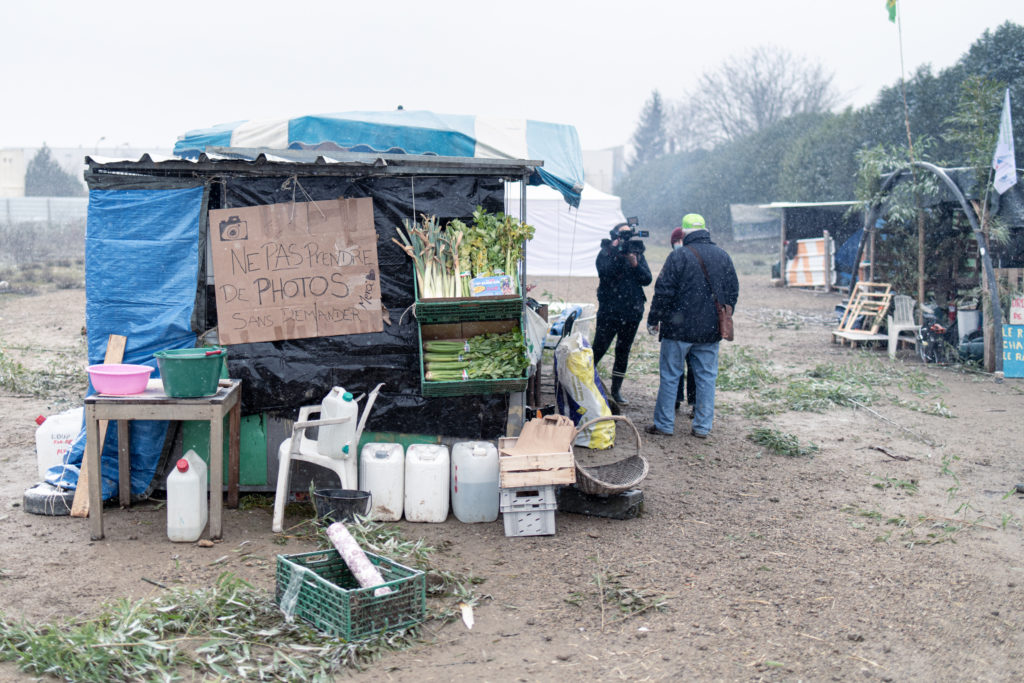 Un militant du Collectif pour le Triangle de Gonesse est interviewé par France 3 à côté de l'abri utilisé pour cuisiné sur la ZAD