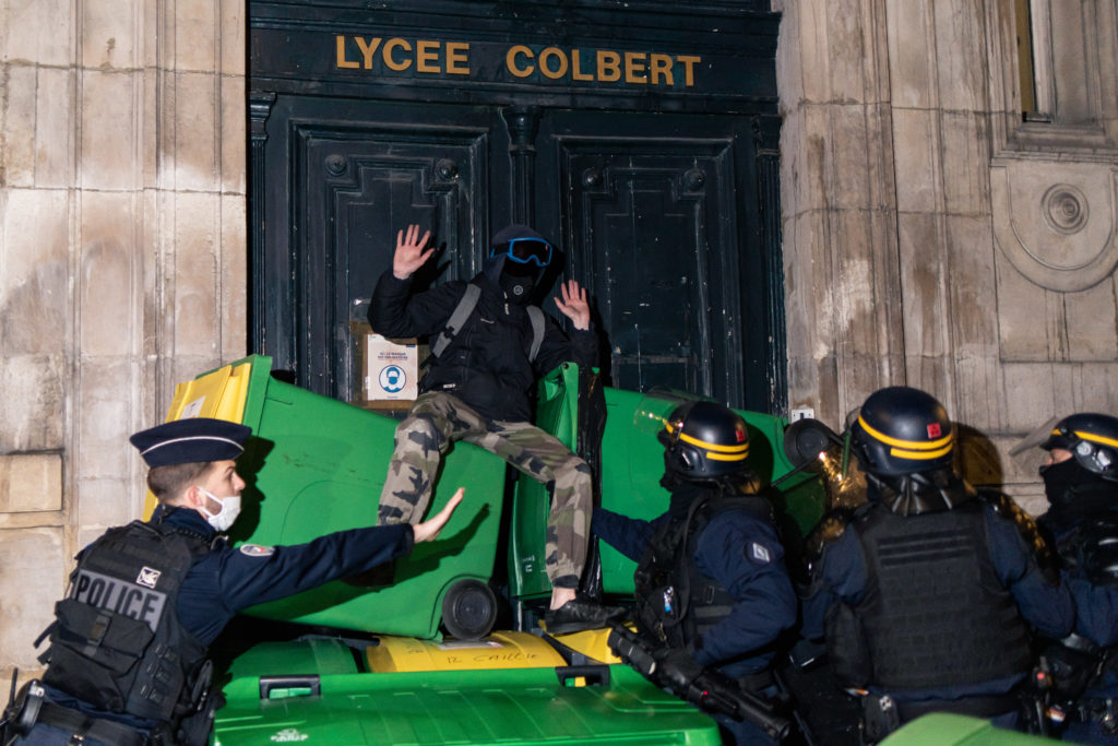 Un policier intime aux CRS de ne pas descendre trop brusquement un lycéen d'une pile de poubelle lors de la tentative de blocus du lycée Colbert dans le 10ème arrondisssement de Paris le 26 janvier 2021