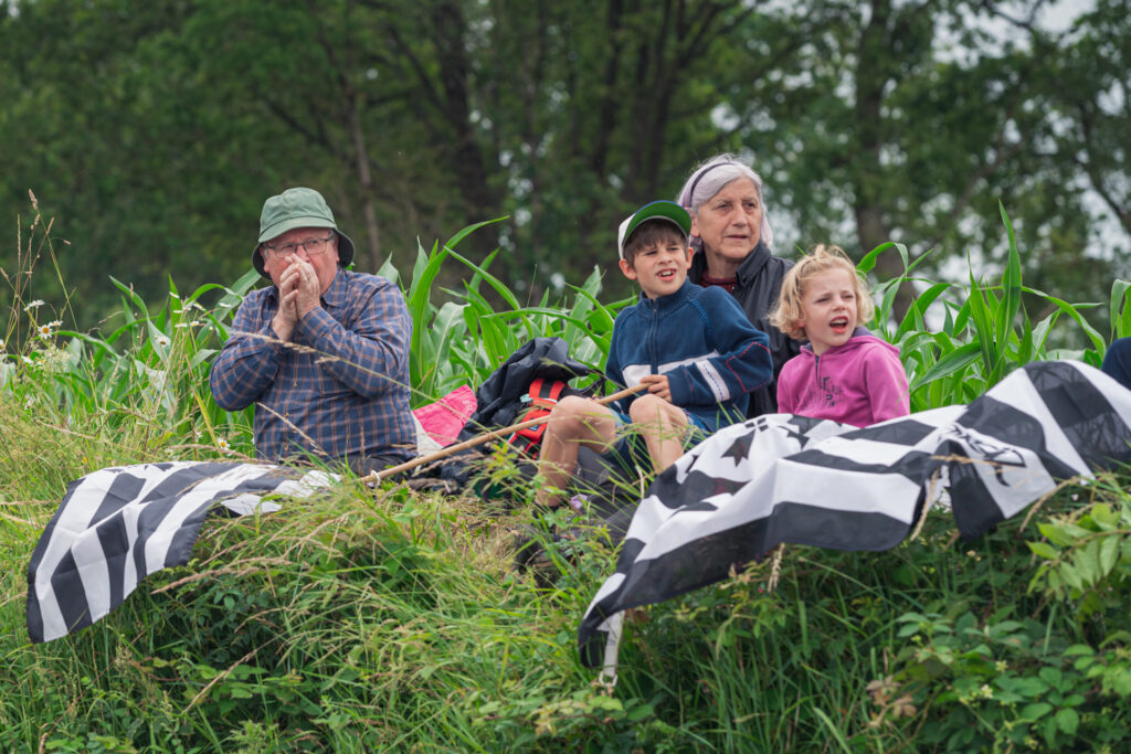 Alors qu'un coureur semble approcher un grand père prépare son sifflet fabriqué avec un brin d'herbe pendant que le reste de la famille guette l'horizon