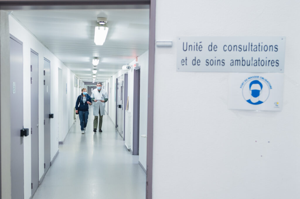 Deux infirmiers de l'EMOT échangent au sujet d'un patient dans le couloir l'unité de consultations et de soins ambulatoires de la maison d'arrêt de Sequedin.