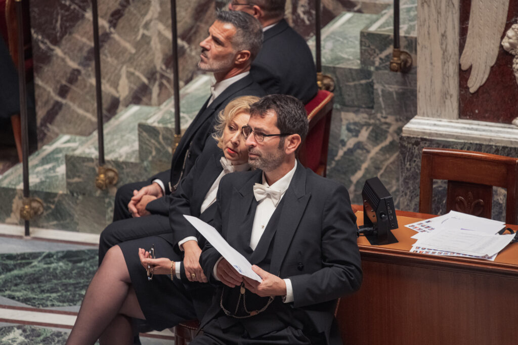 Deux Huissiers de l'Assemblée nationale cherchent un député auquel ils doivent remettre un courrier dans l'hémicycle le 22 novembre 2022.