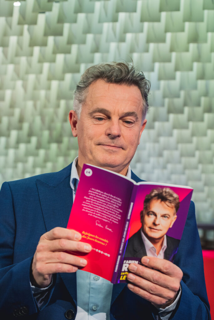 Fabien Roussel, député PCF et candidat à l'élection présidentielle, pose en lisant son livre-programme dit des "jours heureux" à la presse, au siège de son parti le 24 janvier 2022 à Paris