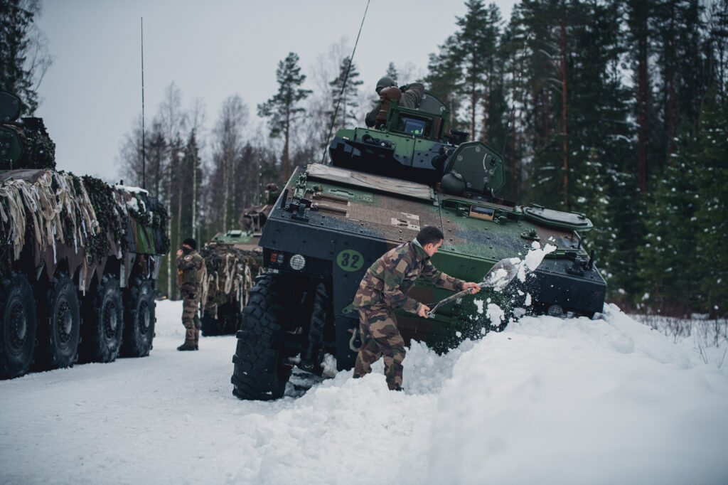 Un conducteur dégage la neige autour de son VBCI ayant glissé dans un fossé enneigé, le 6 février 2022, lors du Winter Camp de l'enhanced Foward Presence Battlegroup de l'OTAN en Estonie.